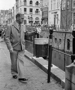 857297 Afbeelding van een man die iets in een prullenbak deponeert op de Vismarkt te Utrecht.